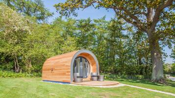 Una piccola struttura in legno a forma di semicirchio, con una porta in vetro e due sedie all'esterno.