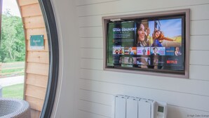 A wall-mounted television displaying a Netflix movie poster, a thermostat, and a sign reading "Bluebell". - Foxtail Glamping Pod - sleeps 2 | Gold Award winning (Pickering)