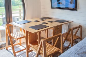 Work and unwind in this stylish room, featuring a large window with a view, a wooden table, and a mounted TV.