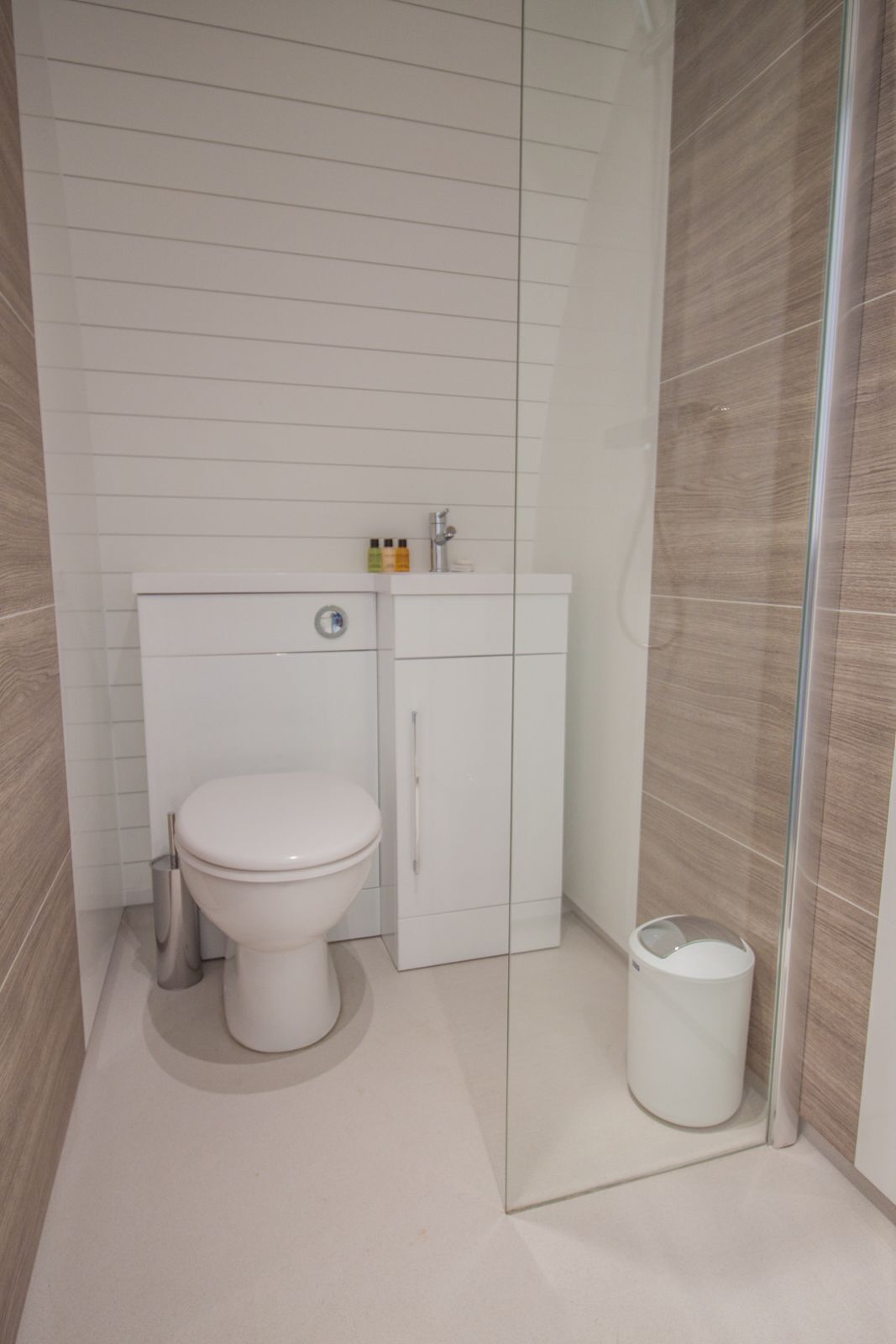 A modern bathroom with a toilet, a cabinet, and a trash bin.
