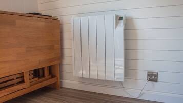 Een witte radiator aan een muur, met een houten kastje eronder.