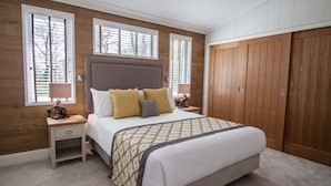 Un dormitorio con una cama grande, un armario de madera y dos mesitas de noche.