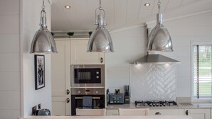 Una cocina moderna con tres lámparas colgantes, un microondas, una estufa y un salpicadero con diseño de espiga.
