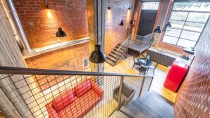 A multi-level interior with exposed brick walls, a staircase, and a dining area with a red accent wall. - Art Loft 04 'On Stage' in Valencia (València)