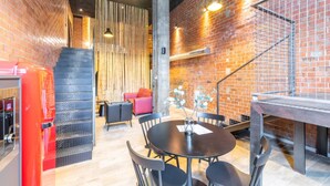 A modern interior with a brick wall, a staircase, a dining area with a round table and chairs, and a red refrigerator. - Art Loft 04 'On Stage' in Valencia (València)