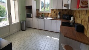 Ett kök med vita skåp, en bänkskiva i trä och ett fönster som släpper in naturligt ljus.
