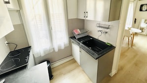 Una cocina compacta con encimera negra, un lavamanos y un mueble pequeño.