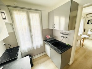 A compact kitchen with a black countertop, a sink, and a small cabinet.