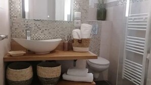 Een badkamer met een vrijstaand bad, toilet en douchehoek.