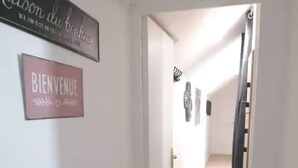 Een hal met een 'BIENVENUE'-bord, een 'Maison du Bonheur'-bord en een deurmat.