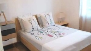 Een slaapkamer met een houten bed, witte beddengoed en een hanglamp.