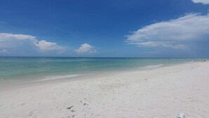 A beach with clear turquoise water and a white sandy shore under a blue sky with scattered clouds. - Fully Renovated! Gulf AND Bay views! Inground Heated Pool! 2 min walk to beach! (Port St. Joe)