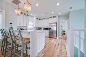 Una cocina moderna con armarios blancos, un refrigerador de acero inoxidable y una isla central.
