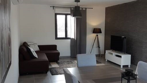 A modern living room with a sofa, dining table, chairs, a TV, and a lamp. - Chalet Bois Piscine Individuelle Dordogne (Saint-Hilaire-d'Estissac)