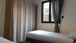 A bedroom with a bed, a window with curtains, and a door with a curtain. - Chalet Bois Piscine Individuelle Dordogne (Saint-Hilaire-d'Estissac)