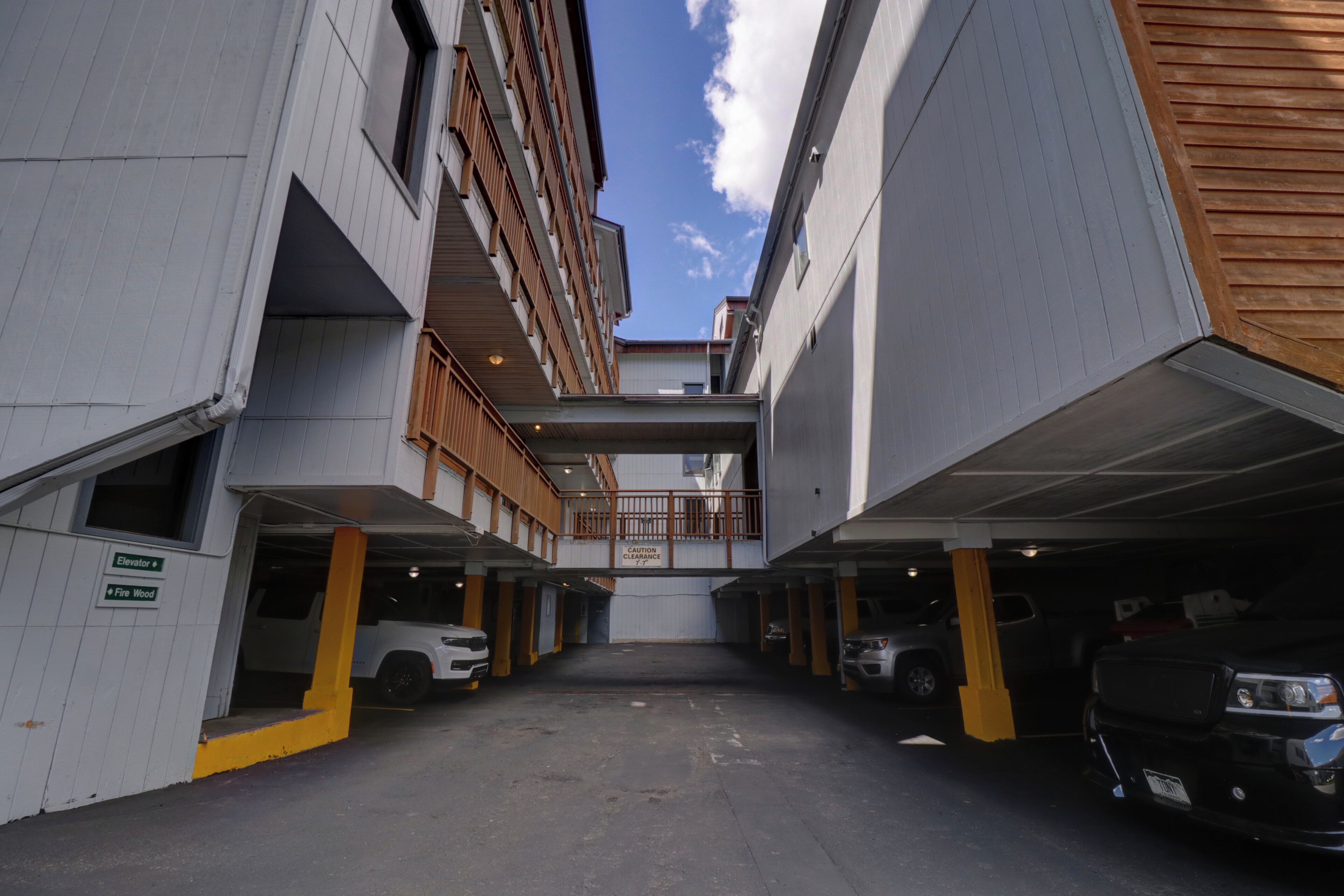 A multi-level parking garage with several cars parked, a visible elevator, and a firewood sign.