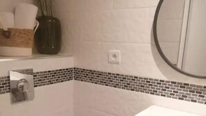 Ein Badezimmer mit einer weißen Toilette, einem Waschbecken mit Spiegel darüber und einer gefliesten Rückwand.