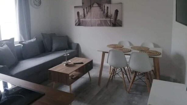 Ein modernes Wohnzimmer mit einer Couch, einem Couchtisch, einem Esstisch mit Stühlen und einem großen Kunstwerk an der Wand.
