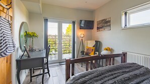 Une chambre à coucher avec un lit, un bureau, une chaise, une télévision et une fenêtre.