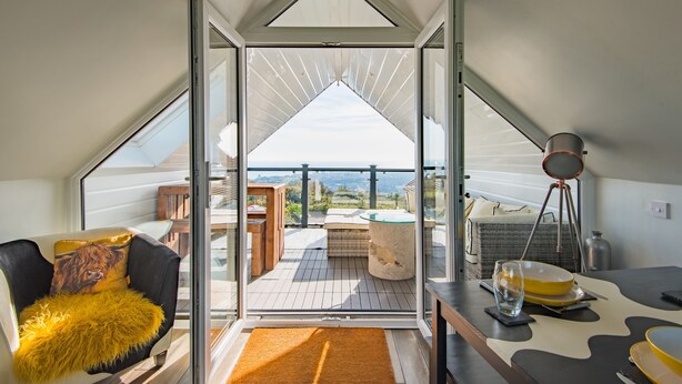 Un intérieur moderne avec une porte vitrée donnant sur une terrasse, un coin salon confortable et un espace repas.