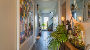 Un couloir agrémenté d’une œuvre d’art murale aux couleurs vives, d’un escalier et d’un dôme de verre décoratif abritant des plantes.