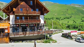 A wooden building with multiple floors, a balcony, and signs for 'SkiSet' and 'Savoyard Bar, Pizzeria'. - 4/6-person apartment in Saint-Sorlin-d'Arves at the foot of the slopes (Saint-Sorlin-d'Arves)