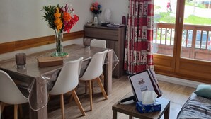 A modern living room with a dining area, a flat-screen TV, a wooden dining table, and a sofa. - 4/6-person apartment in Saint-Sorlin-d'Arves at the foot of the slopes (Saint-Sorlin-d'Arves)
