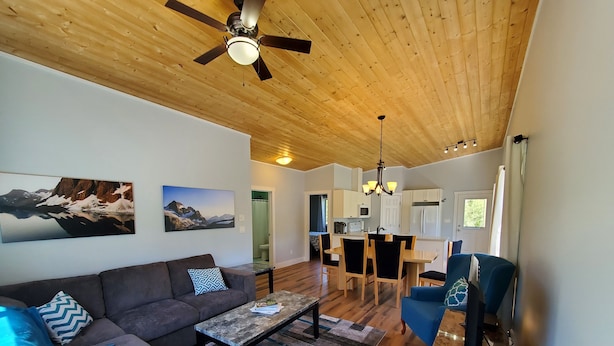 Uma sala de estar moderna com sofá, mesa de centro e um espaço de jantar com cadeiras e mesa.