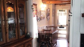 Ein Holztisch mit Stühlen, ein Holzschrank und ein Fenster mit Vorhängen.