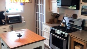 Eine kleine Küche mit einer Holzinsel, einem Gasherd, einer Mikrowelle und einem Toaster.