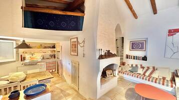 Una sala de estar acogedora con chimenea, un comedor con cocina al fondo y un altillo superior.