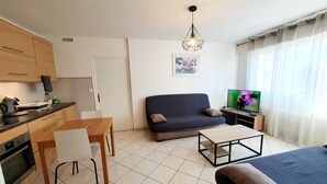 Un espacio habitable compacto con kitchenette, un sofá, una mesa de comedor y un televisor.