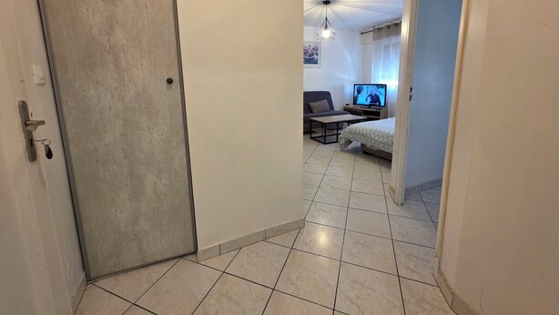 Un pasillo que conduce a una sala de estar con sofá, televisión y cama.