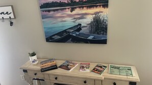 A desk with a scenic lake painting, a potted plant, and several welcome brochures. - Lake view house with private pier lake access (Knox)