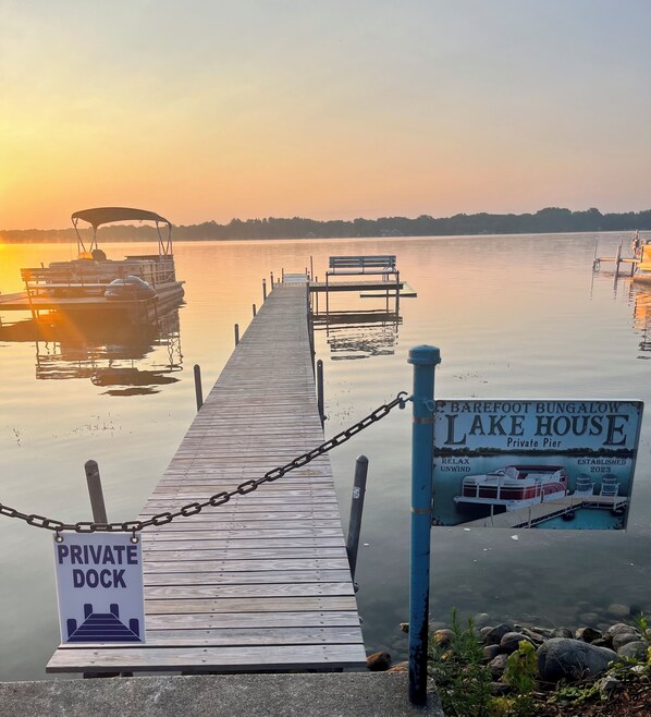 Une jetée en bois menant à un quai privé, sur lequel on peut lire l’inscription « Quai privé de la maison de vacances Barefoot Bungalow, au bord du lac », ainsi qu’un panneau indiquant « Quai privé ».