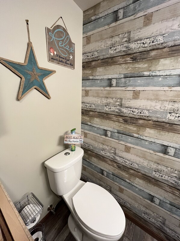 A bathroom with a rustic wooden wall, a star decoration, and a sign that reads "Best seat in the house".
