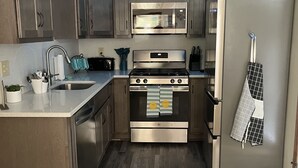 A modern kitchen with stainless steel appliances, wooden cabinets, and a blue accent wall.