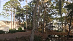 A residential area with a large house featuring a deck and a pond. - Hilton Head with 4 rounds of golf and tennis a day included!!!! (Hilton Head Island)