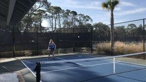 A tennis court with a net, surrounded by a fence and trees. - Hilton Head with 4 rounds of golf and tennis a day included!!!! (Hilton Head Island)