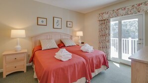 A double room with two beds, a wooden headboard, bedside lamps, a small drawer, and a view of a balcony through a glass door. - Hilton Head with 4 rounds of golf and tennis a day included!!!! (Hilton Head Island)