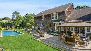 A backyard with a swimming pool, patio furniture, and a covered seating area. - Hamptons Summer Rental - secluded pool + 5 minutes to beach (East Quogue)