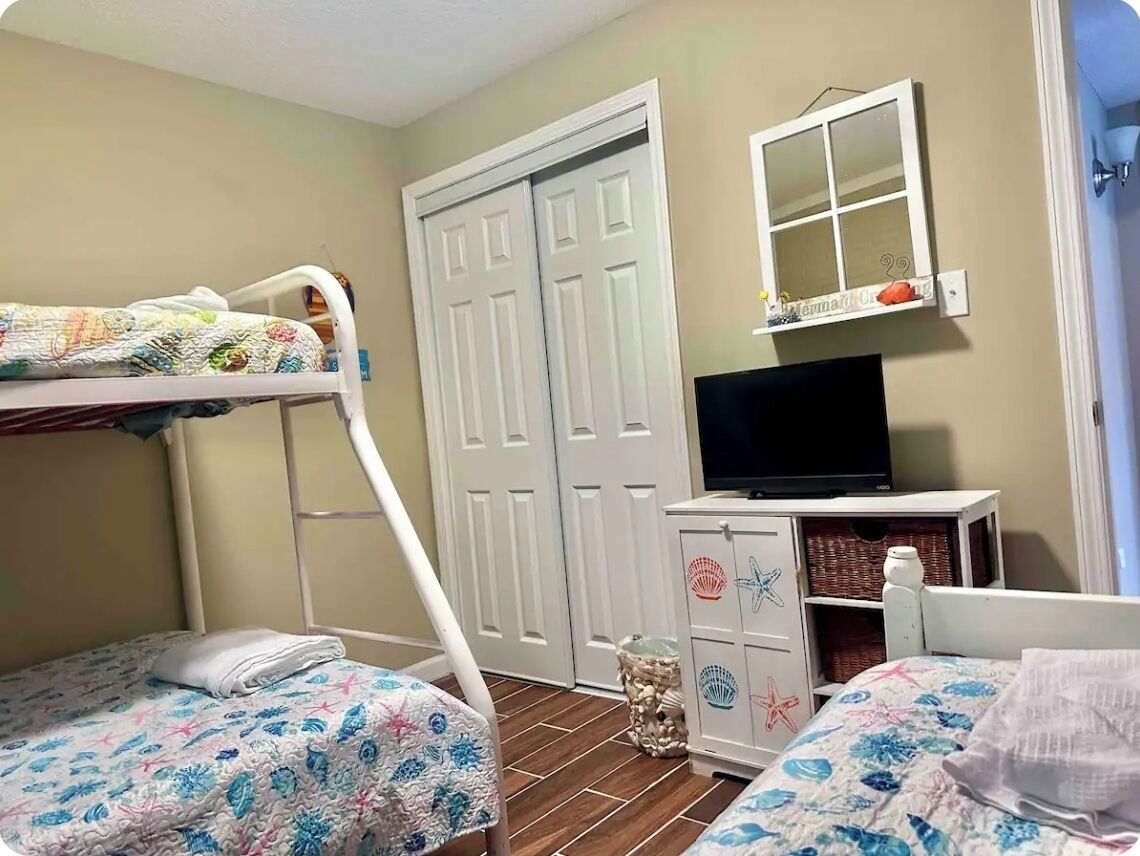 A bedroom with bunk beds, a television, and a wardrobe.
