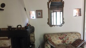 Ein Zimmer mit Kamin, einem blumigen Sofa und einem Spiegel an der Wand.
