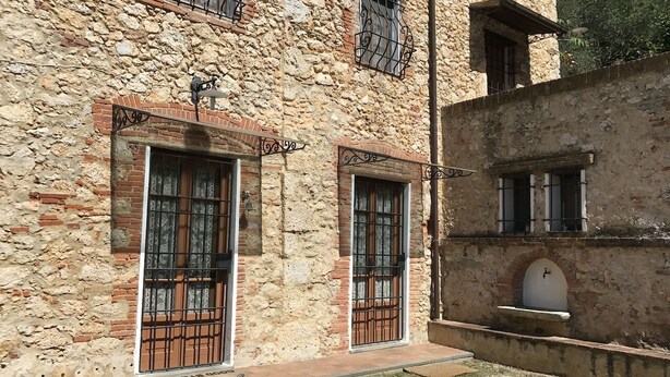 Ein Steinhaus mit zwei Portalen, jedes mit einem Metallgitter und einem kleinen Fenster darüber.
