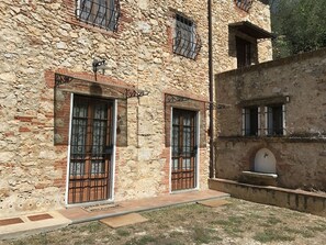 A stone building with two doors, each with a metal gate and a small window above. - Casa Rurale Finemente Ristrutturata Risalente a Fine del 17 Secolo (Camaiore)
