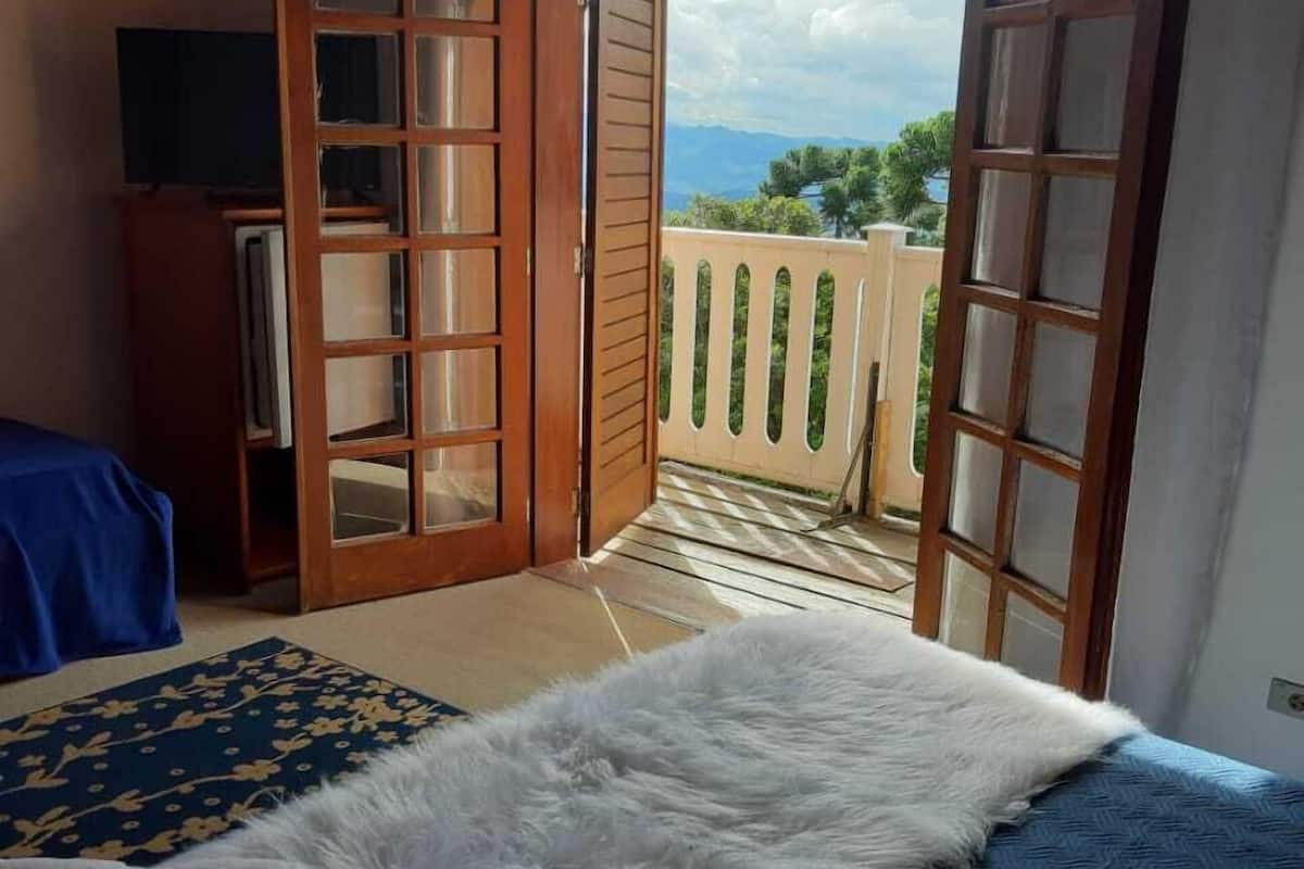 A bedroom with a bed, a television, and a view of the outdoors through open doors.