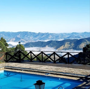 A pool with a view of mountains and a clear sky. - Pousada Village Pôr do Sol (Campos do Jordão)