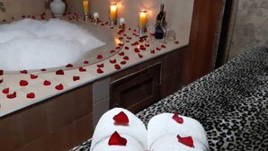 Um banheiro com banheira, velas e pétalas de rosa.