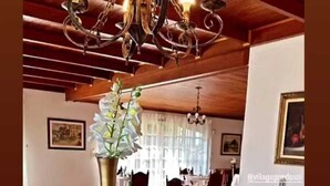 Uma sala de jantar com mesa de madeira posta para refeição, exibindo diversos doces e sobremesas.