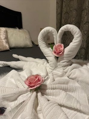 A bed with a white, textured blanket and two pink roses placed on it. - Pousada Village Pôr do Sol (Campos do Jordão)